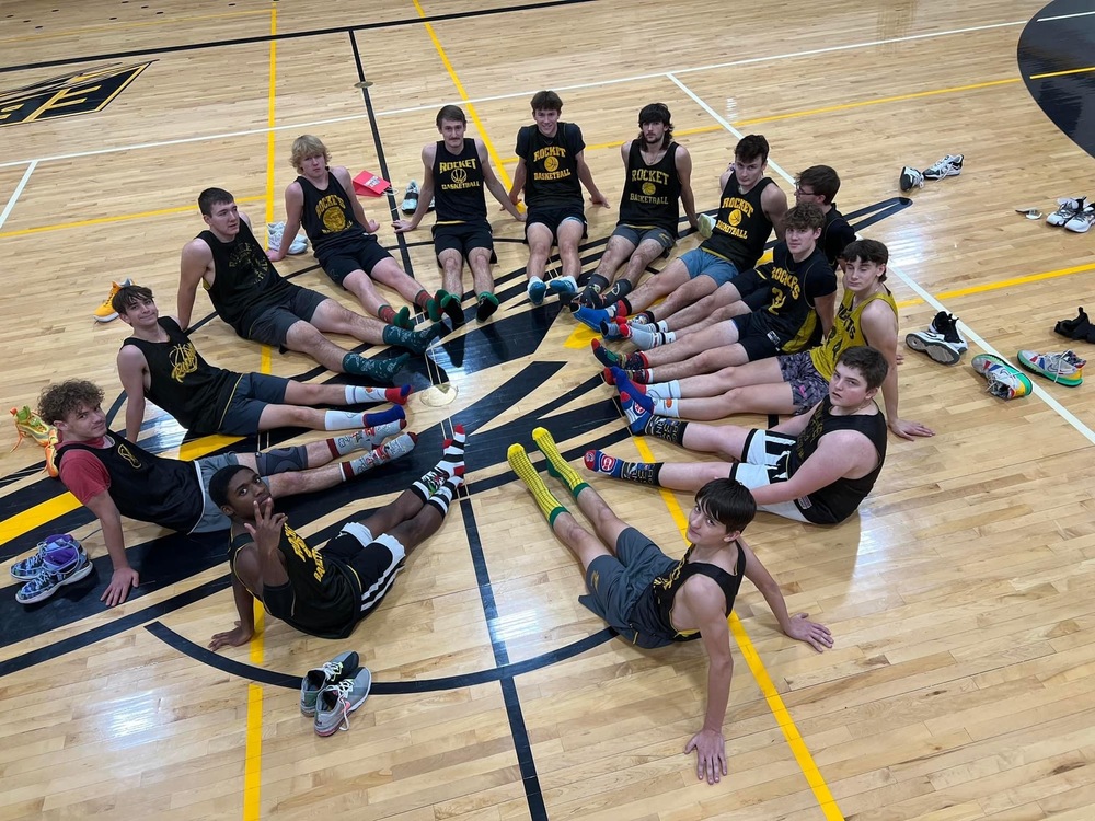 Image of EBF boys basketball team sitting on the floor at the EBF high school gymnasium